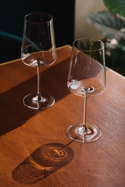 棕色木桌上的2个透明酒杯